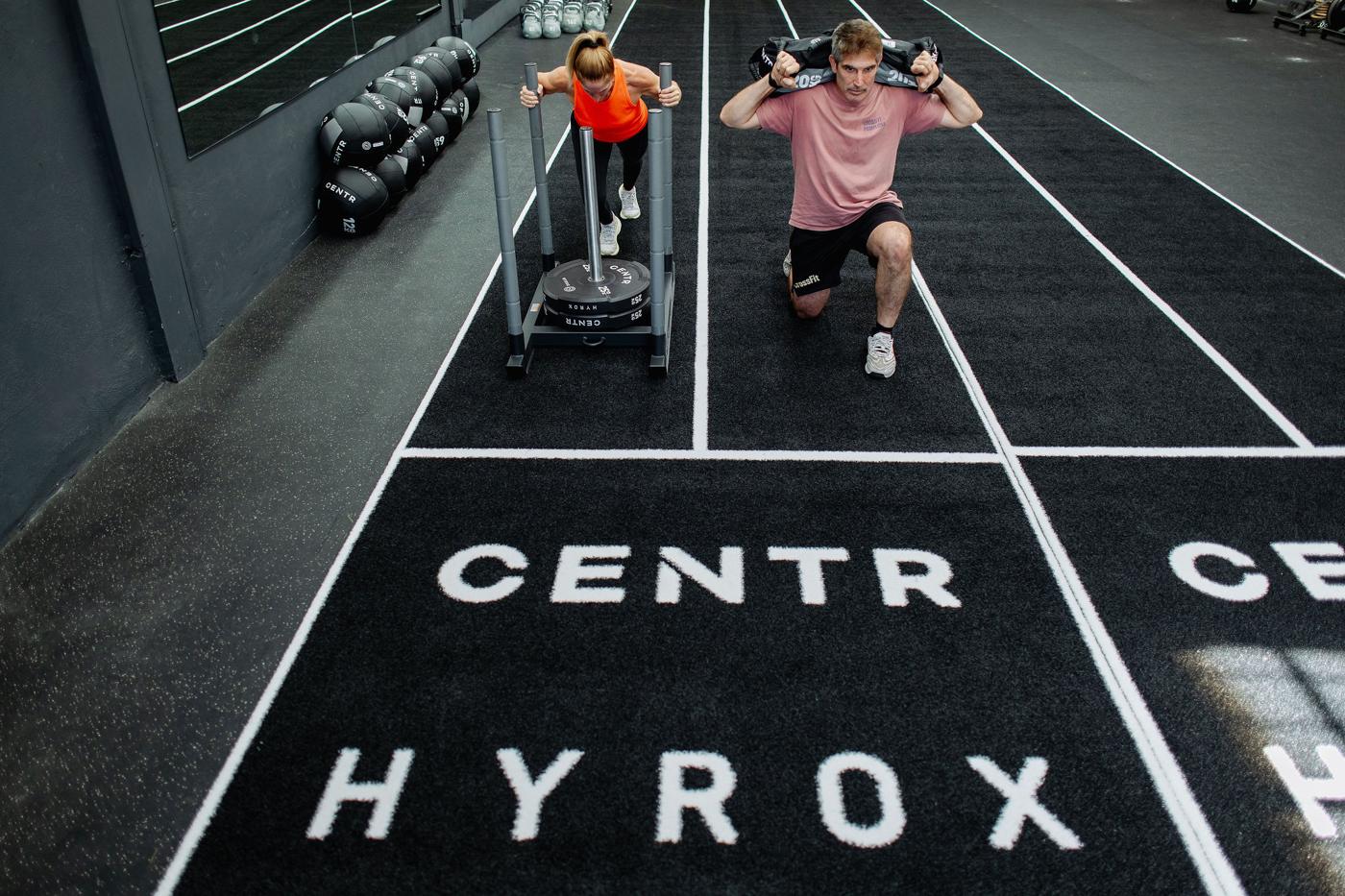 Trineo y sandbag lunges sobre la pista Centr HYROX